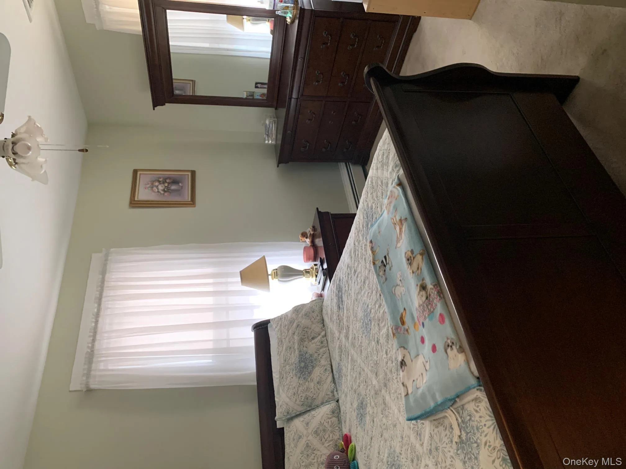 Bedroom featuring light carpet, ceiling fan, and a baseboard heating unit Bedroom featuring light carpet, ceiling fan, and a baseboard heating unit