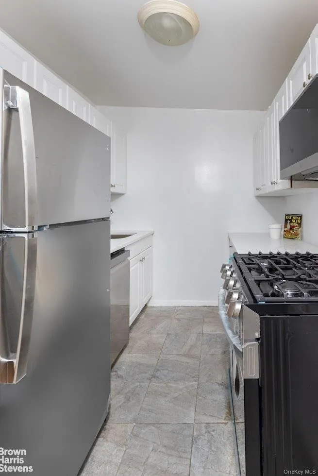 Kitchen featuring appliances with stainless steel finishes, white cabinetry, and light countertops Kitchen featuring appliances with stainless steel finishes, white cabinetry, and light countertops