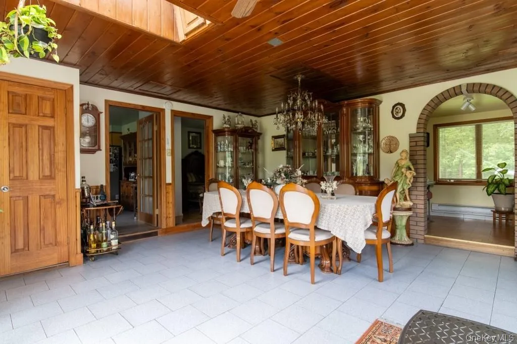 Dining room featuring wooden ceiling, a chandelier, ornamental molding, and a baseboard radiator Dining room featuring wooden ceiling, a chandelier, ornamental molding, and a baseboard radiator