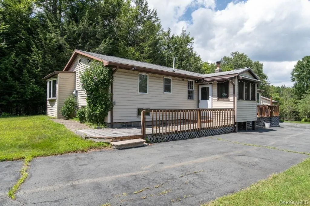 Ranch-style home with a wooden deck and a front yard Ranch-style home with a wooden deck and a front yard