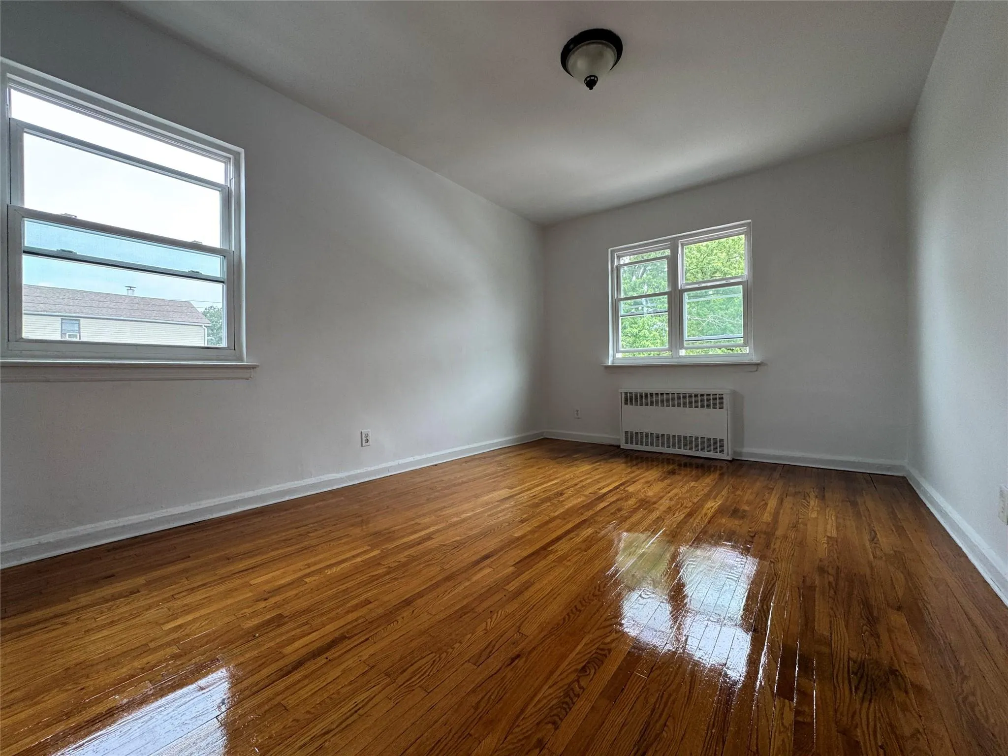Empty room featuring radiator and hardwood / wood-style flooring Empty room featuring radiator and hardwood / wood-style flooring