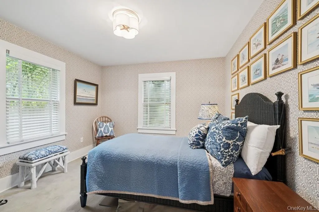 Bedroom with multiple windows, wallpapered walls, and wood finished floors Bedroom with multiple windows, wallpapered walls, and wood finished floors
