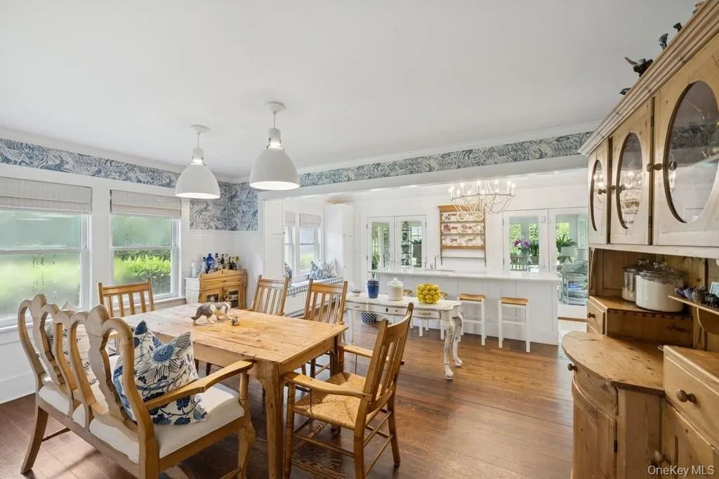 Dining room with dark wood-type flooring, a chandelier, ornamental molding, wallpapered walls, and wainscoting Dining room with dark wood-type flooring, a chandelier, ornamental molding, wallpapered walls, and wainscoting
