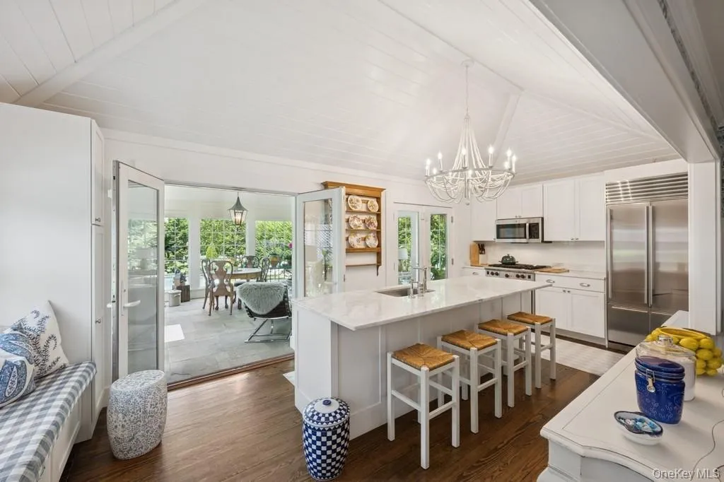 Kitchen featuring stainless steel appliances, a chandelier, dark wood-type flooring, white cabinetry, and an island with sink Kitchen featuring stainless steel appliances, a chandelier, dark wood-type flooring, white cabinetry, and an island with sink