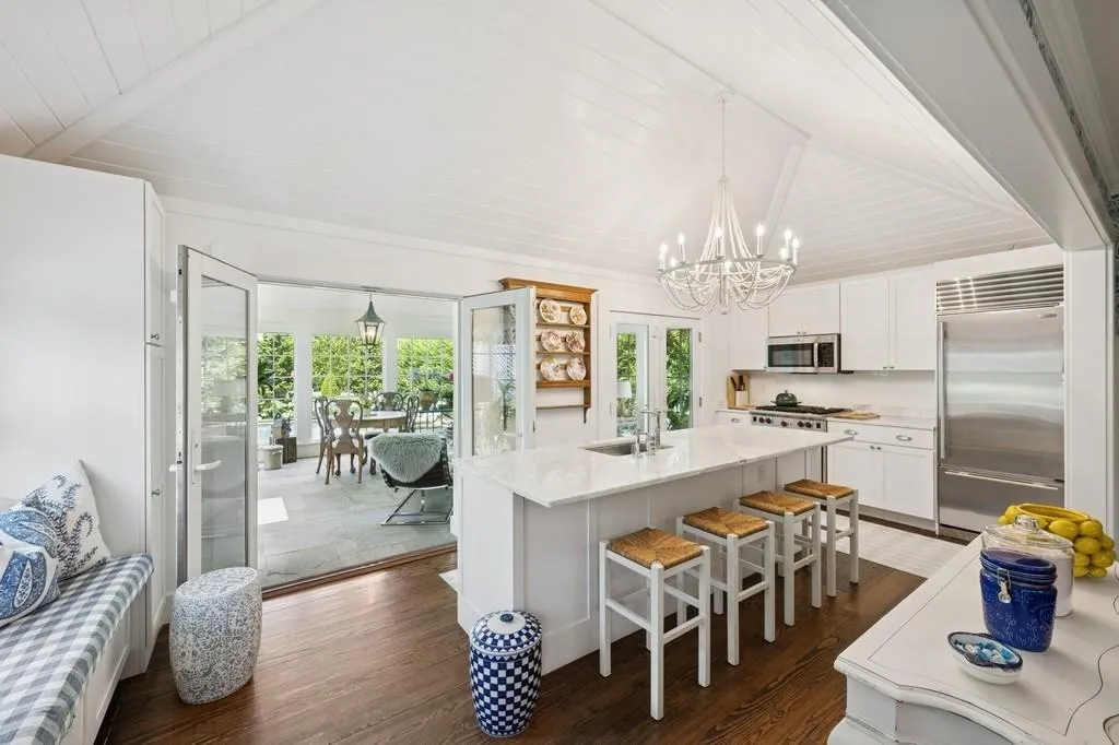 Kitchen featuring stainless steel appliances, a chandelier, dark wood-style floors, white cabinetry, and an island with sink Kitchen featuring stainless steel appliances, a chandelier, dark wood-style floors, white cabinetry, and an island with sink