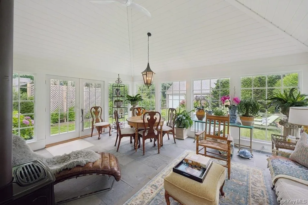 Sunroom / solarium featuring french doors, high vaulted ceiling, and stone finish floors Sunroom / solarium featuring french doors, high vaulted ceiling, and stone finish floors