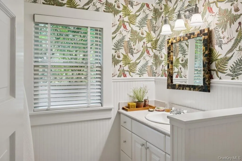 Bathroom with wainscoting, vanity, and wallpapered walls Bathroom with wainscoting, vanity, and wallpapered walls