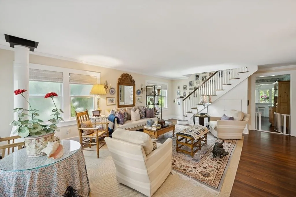 Living room with stairs, ornamental molding, plenty of natural light, and wood finished floors Living room with stairs, ornamental molding, plenty of natural light, and wood finished floors