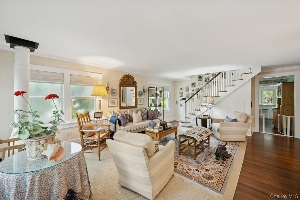 Living room with stairs, ornamental molding, plenty of natural light, and wood finished floors Living room with stairs, ornamental molding, plenty of natural light, and wood finished floors