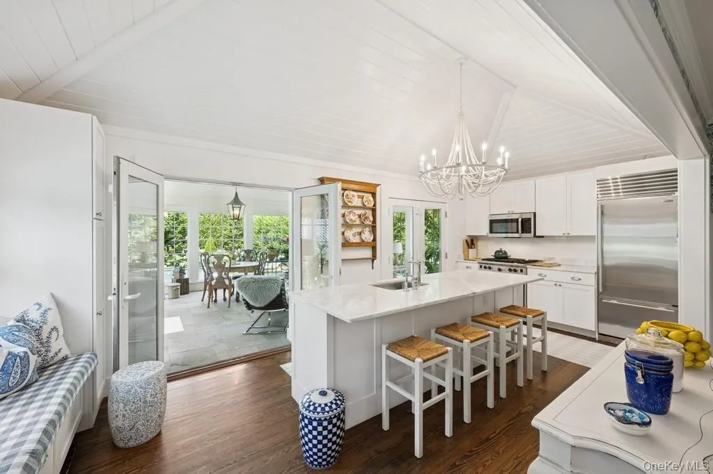 Kitchen featuring stainless steel appliances, a chandelier, dark wood-style floors, white cabinetry, and an island with sink Kitchen featuring stainless steel appliances, a chandelier, dark wood-style floors, white cabinetry, and an island with sink