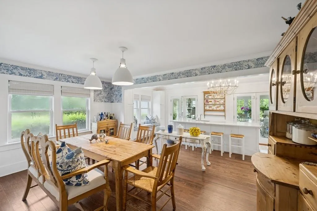 Dining room with wood finished floors, wallpapered walls, crown molding, and a chandelier Dining room with wood finished floors, wallpapered walls, crown molding, and a chandelier