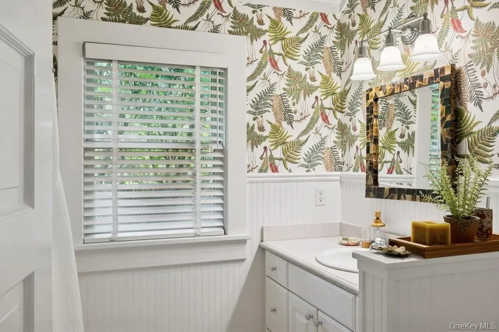 Bathroom with wainscoting, vanity, and wallpapered walls Bathroom with wainscoting, vanity, and wallpapered walls