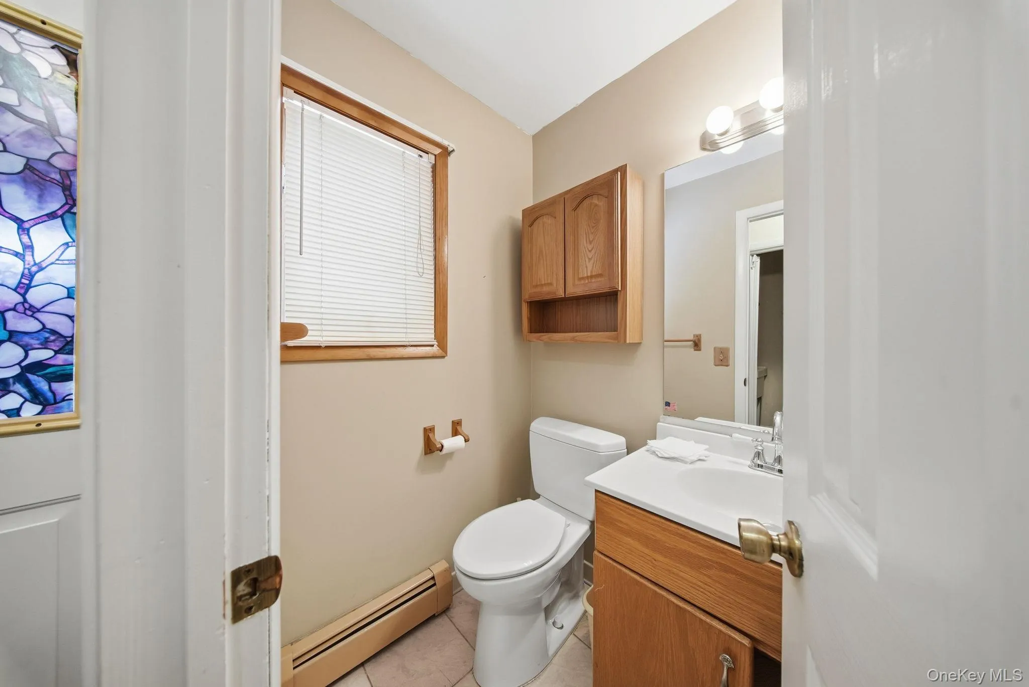 Half bathroom with baseboard heating, vanity, and light tile patterned flooring Half bathroom with baseboard heating, vanity, and light tile patterned flooring