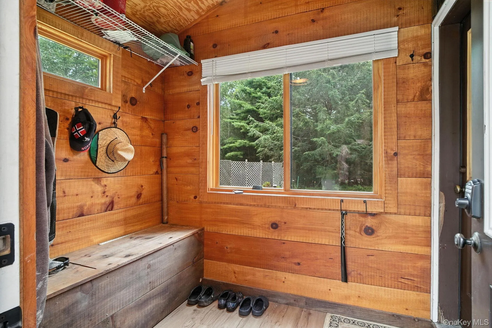 Mudroom with wooden walls, vaulted ceiling, and wood finished floors Mudroom with wooden walls, vaulted ceiling, and wood finished floors