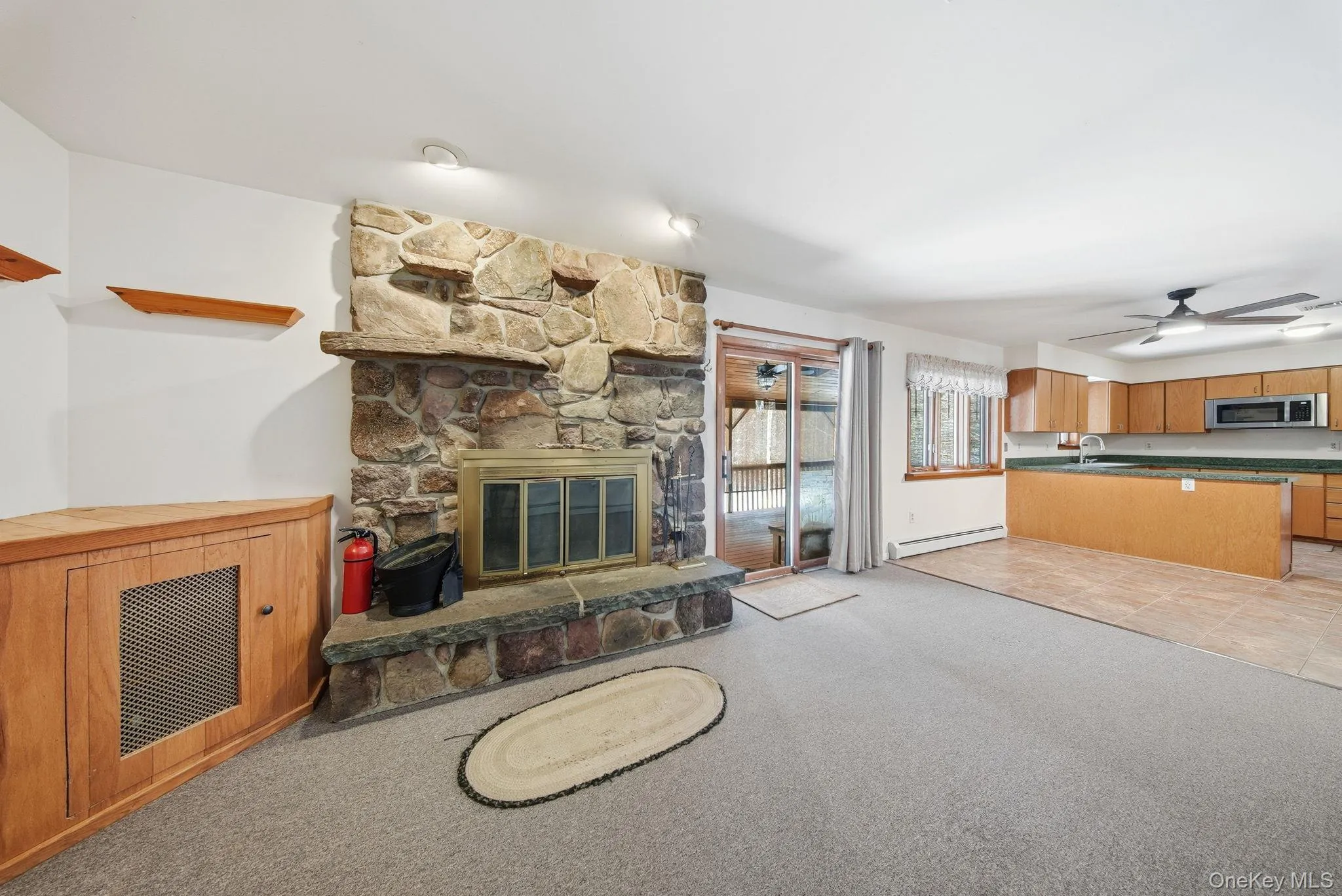 Featuring a hand picked fieldstone fireplace, light colored carpet, a baseboard heating Featuring a hand picked fieldstone fireplace, light colored carpet, a baseboard heating