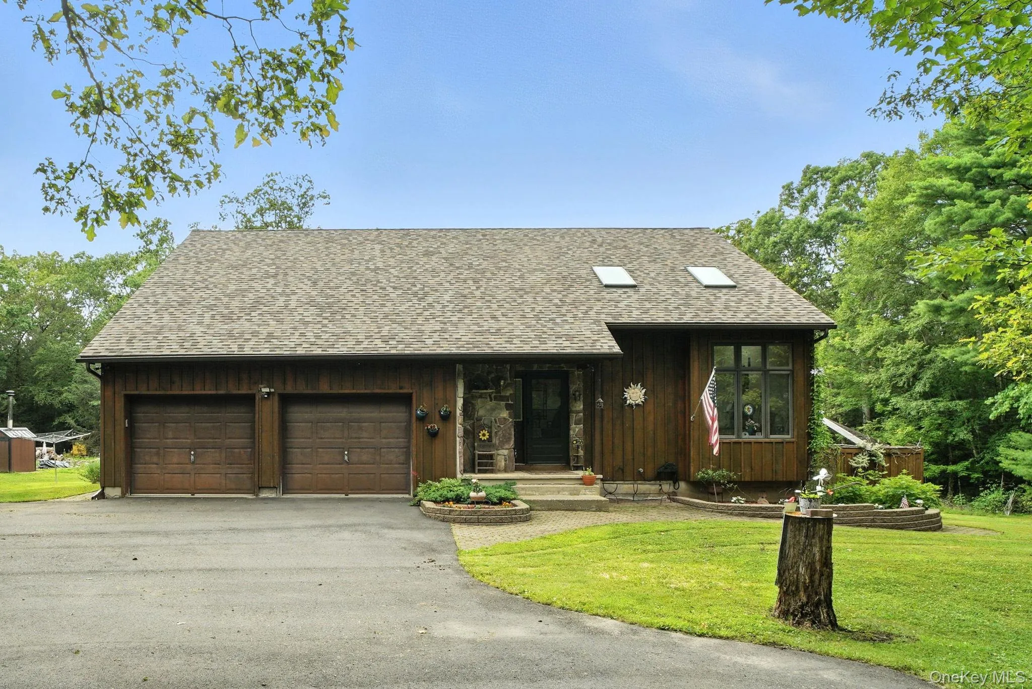 Rustic Pine Siding home featuring an attached garage, a front lawn, asphalt driveway, and roof with shingles Rustic Pine Siding home featuring an attached garage, a front lawn, asphalt driveway, and roof with shingles