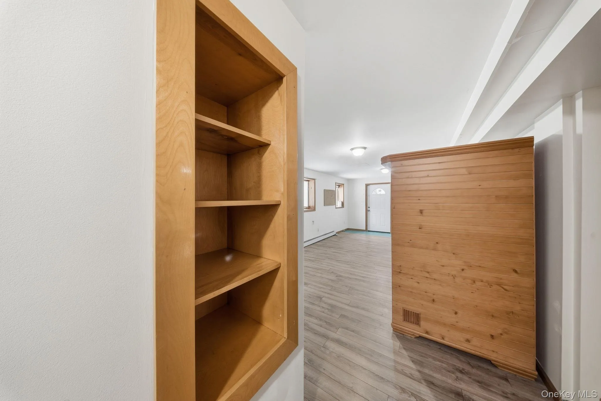 Corridor with light wood-style floors and a baseboard heating unit Corridor with light wood-style floors and a baseboard heating unit