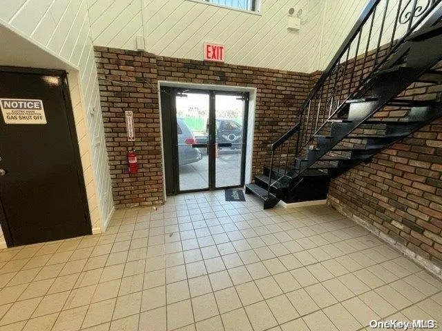 Tiled entryway featuring brick wall, healthy amount of natural light, a high ceiling, and stairs Tiled entryway featuring brick wall, healthy amount of natural light, a high ceiling, and stairs