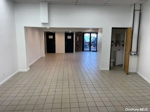 Hallway featuring light tile patterned floors and a paneled ceiling Hallway featuring light tile patterned floors and a paneled ceiling