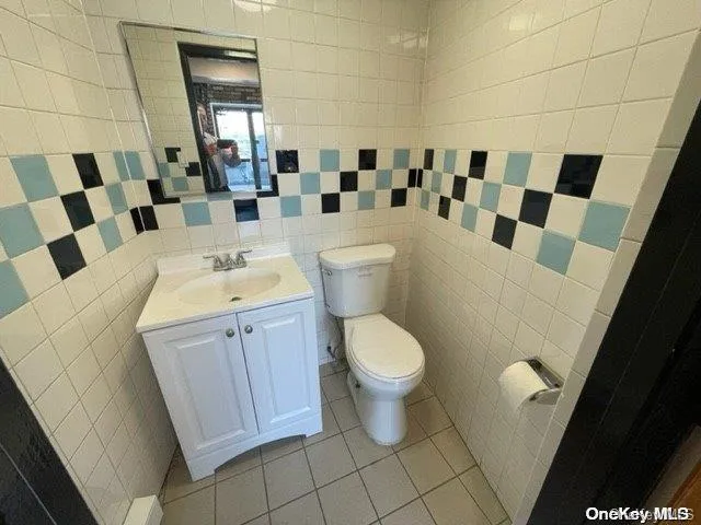 Bathroom featuring vanity, tile patterned flooring, and tile walls Bathroom featuring vanity, tile patterned flooring, and tile walls