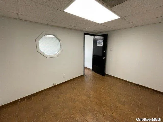 Empty room featuring a drop ceiling and baseboards Empty room featuring a drop ceiling and baseboards