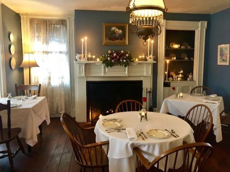 Dining room with wood-type flooring, a lit fireplace, and a chandelier Dining room with wood-type flooring, a lit fireplace, and a chandelier