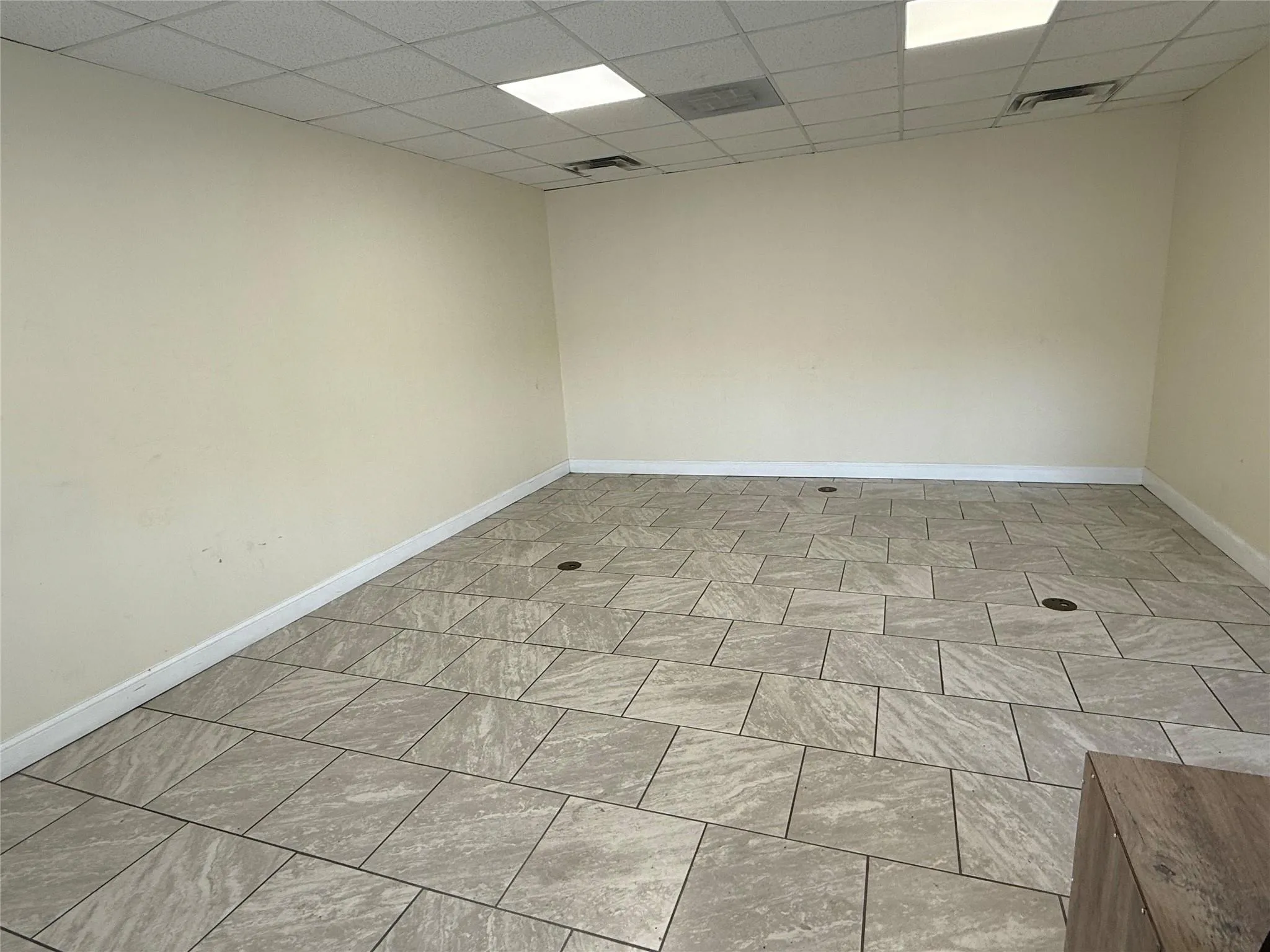 Unfurnished room with a drop ceiling and baseboards Unfurnished room with a drop ceiling and baseboards