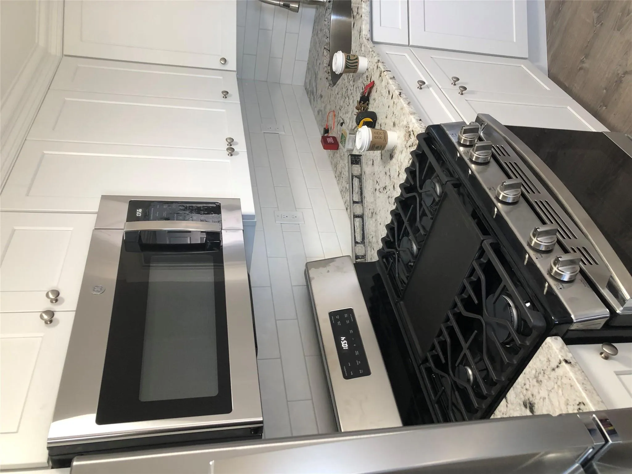 Kitchen with stove, decorative backsplash, refrigerator, white cabinets, and light stone countertops Kitchen with stove, decorative backsplash, refrigerator, white cabinets, and light stone countertops