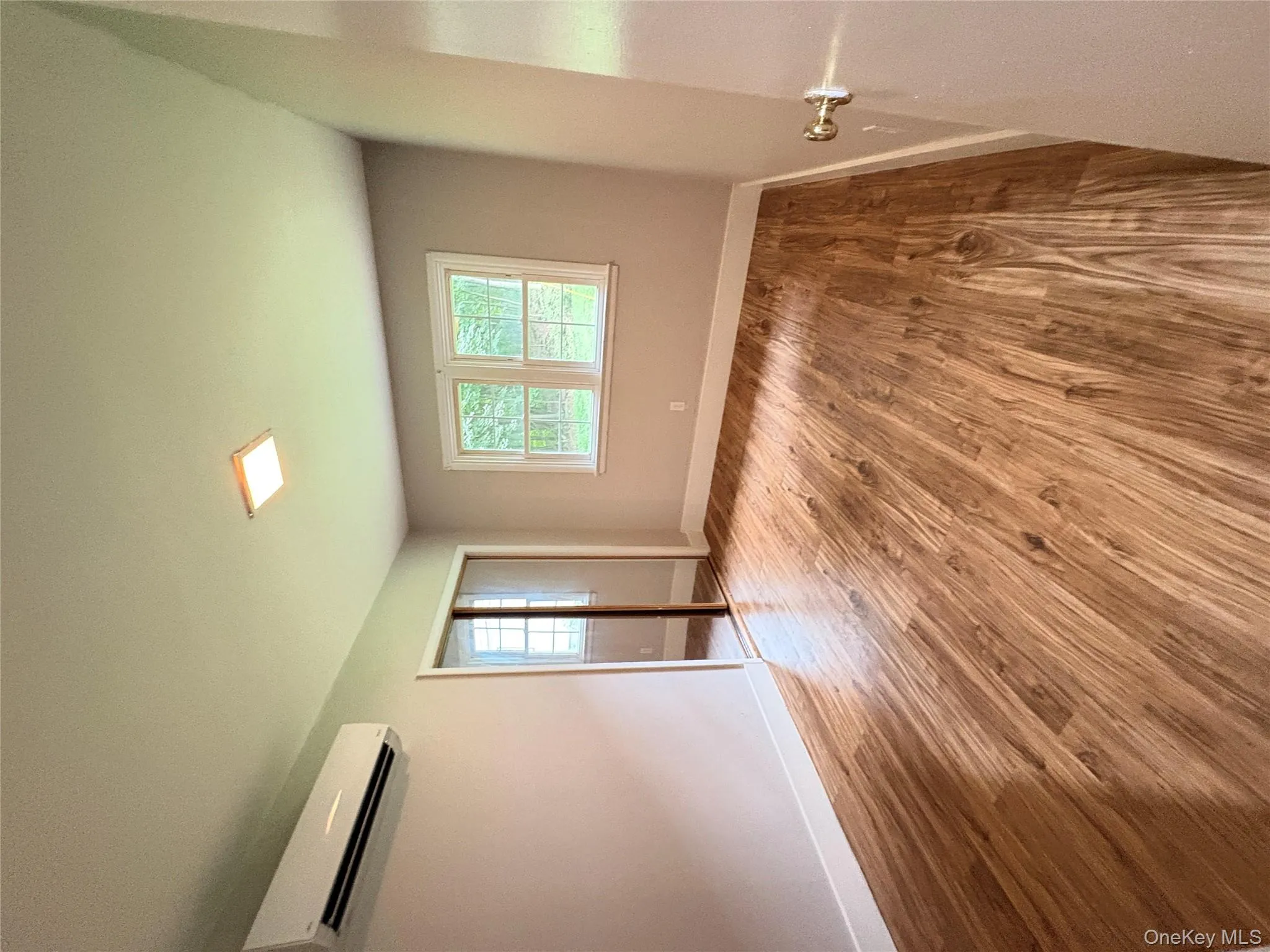 Empty room featuring a wall mounted air conditioner and wood finished floors Empty room featuring a wall mounted air conditioner and wood finished floors