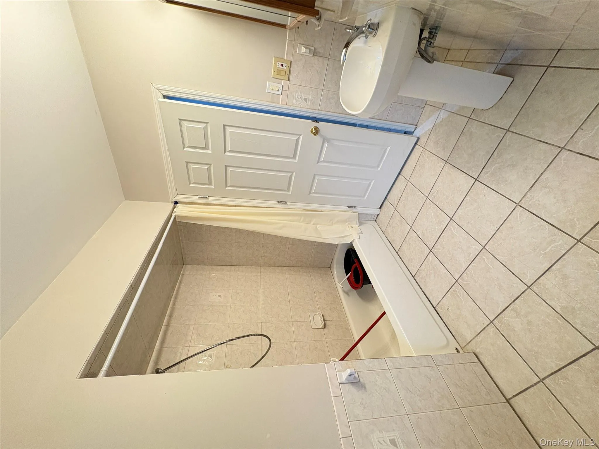 Full bathroom with tile walls, tile patterned flooring, shower / tub combo, and wainscoting Full bathroom with tile walls, tile patterned flooring, shower / tub combo, and wainscoting