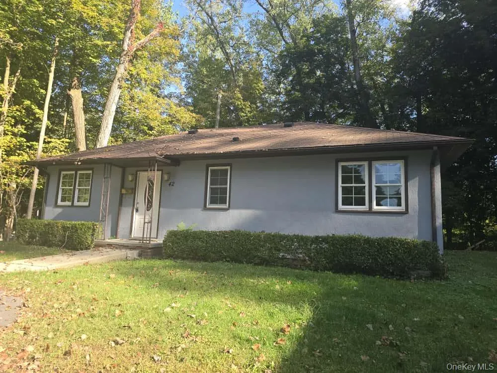 Single story home featuring a front lawn, stucco siding, and view of scattered trees Single story home featuring a front lawn, stucco siding, and view of scattered trees