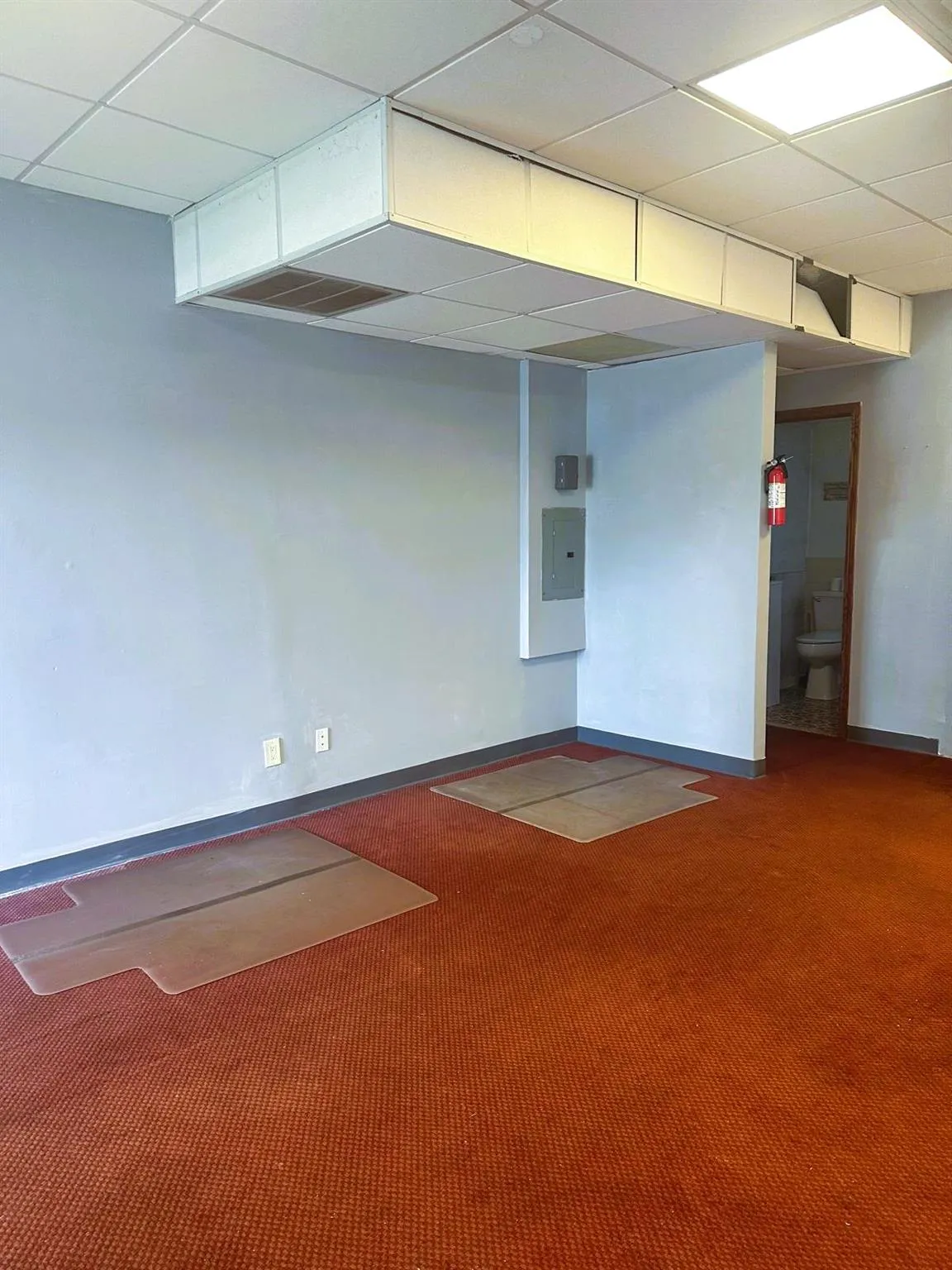 Carpeted empty room featuring a paneled ceiling and electric panel Carpeted empty room featuring a paneled ceiling and electric panel
