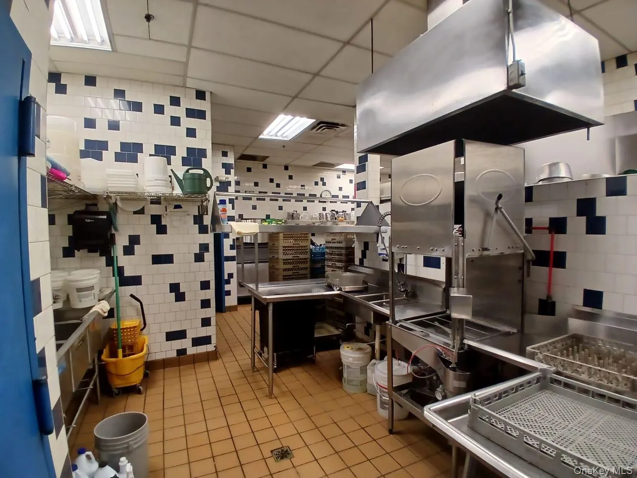 Kitchen featuring tile patterned floors, tile walls, a drop ceiling, and island range hood Kitchen featuring tile patterned floors, tile walls, a drop ceiling, and island range hood