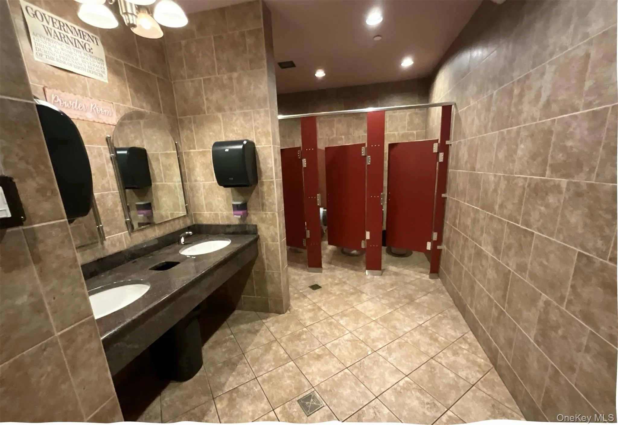 Full bath with tile walls, tile patterned flooring, double vanity, a chandelier, and recessed lighting Full bath with tile walls, tile patterned flooring, double vanity, a chandelier, and recessed lighting