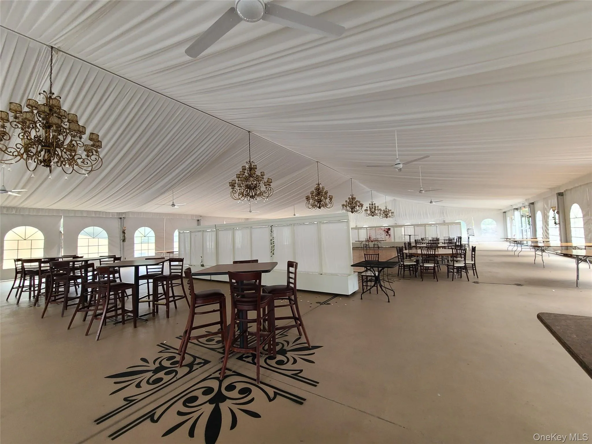 Dining room with a ceiling fan, finished concrete flooring, healthy amount of natural light, vaulted ceiling, and a chandelier Dining room with a ceiling fan, finished concrete flooring, healthy amount of natural light, vaulted ceiling, and a chandelier