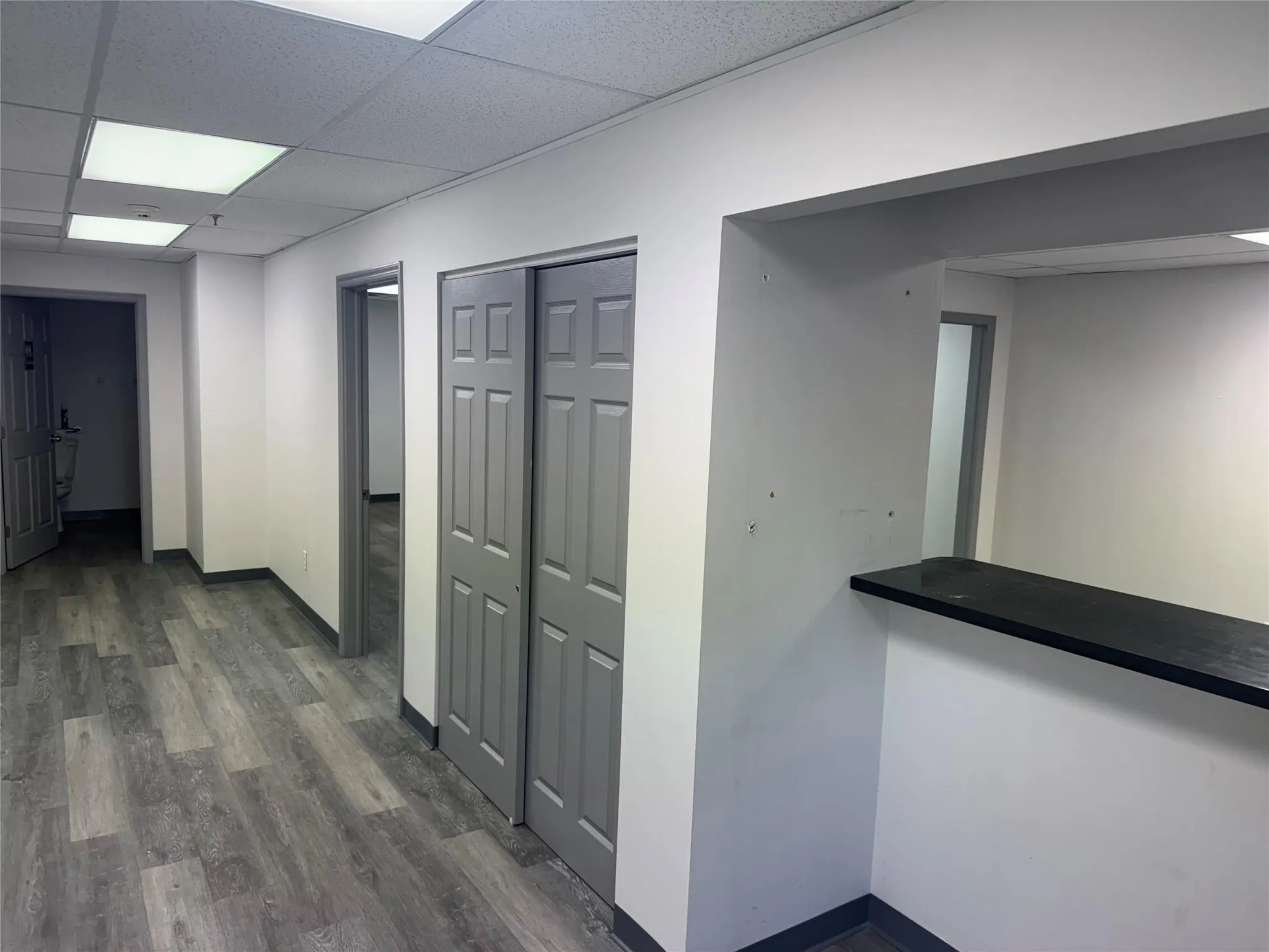 Corridor featuring dark wood-style flooring and a paneled ceiling Corridor featuring dark wood-style flooring and a paneled ceiling