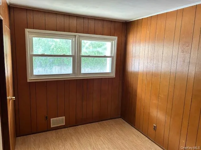 Unfurnished room featuring light wood-style floors and wooden walls Unfurnished room featuring light wood-style floors and wooden walls