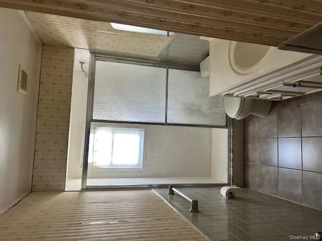 Bathroom with wallpapered walls, a stall shower, vanity, and tile patterned flooring Bathroom with wallpapered walls, a stall shower, vanity, and tile patterned flooring