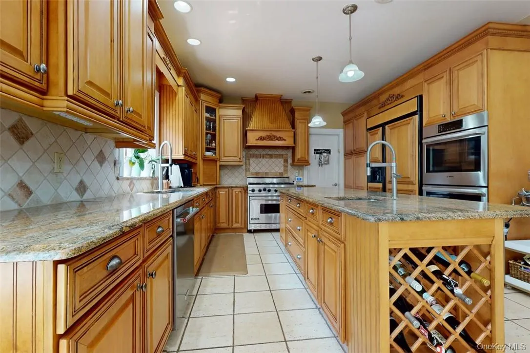 Kitchen with decorative backsplash, high quality appliances, an island with sink, premium range hood, wine rack, and light tile patterned ceramic floors Kitchen with decorative backsplash, high quality appliances, an island with sink, premium range hood, wine rack, and light tile patterned ceramic floors