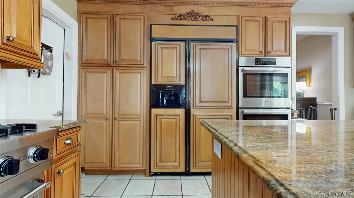 Kitchen with light tile patterned floors, stainless steel appliances, and light stone countertops. Built- in pantry cabinet with lots of shelving. Kitchen with light tile patterned floors, stainless steel appliances, and light stone countertops. Built- in pantry cabinet with lots of shelving.