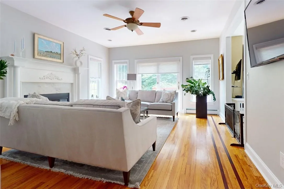 Living room featuring ceiling fan, baseboard heating, and light hardwood / wood-style floors Living room featuring ceiling fan, baseboard heating, and light hardwood / wood-style floors