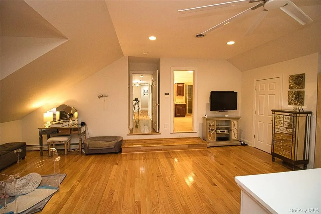 Living room featuring ceiling fan, wood-type flooring, and lofted ceiling Living room featuring ceiling fan, wood-type flooring, and lofted ceiling