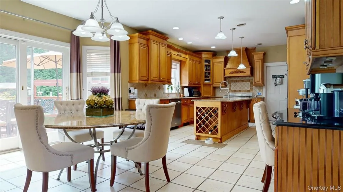 Gorgeous high-end Kitchen featuring Bosch double wall ovens, enormous island with sink, built-in style refrigerator, Stainless steel Viking gas range, st. steel dishwasher, built-in trash bin in island, big granite kitchen table that seats 5-6 people, custom pantry cabinet, desk,st. steel dishwasher, ceramic backsplash, glass-front cabinets, light tile patterned ceramic floors, and designer lighting over island and table, plus recessed lighting Gorgeous high-end Kitchen featuring Bosch double wall ovens, enormous island with sink, built-in style refrigerator, Stainless steel Viking gas range, st. steel dishwasher, built-in trash bin in island, big granite kitchen table that seats 5-6 people, custom pantry cabinet, desk,st. steel dishwasher, ceramic backsplash, glass-front cabinets, light tile patterned ceramic floors, and designer lighting over island and table, plus recessed lighting