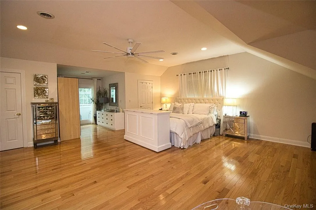 En-Suite primary bedroom with vaulted ceiling, beautiful new ceiling fan, alcove,sitting room, dressing area, and wood flooring En-Suite primary bedroom with vaulted ceiling, beautiful new ceiling fan, alcove,sitting room, dressing area, and wood flooring