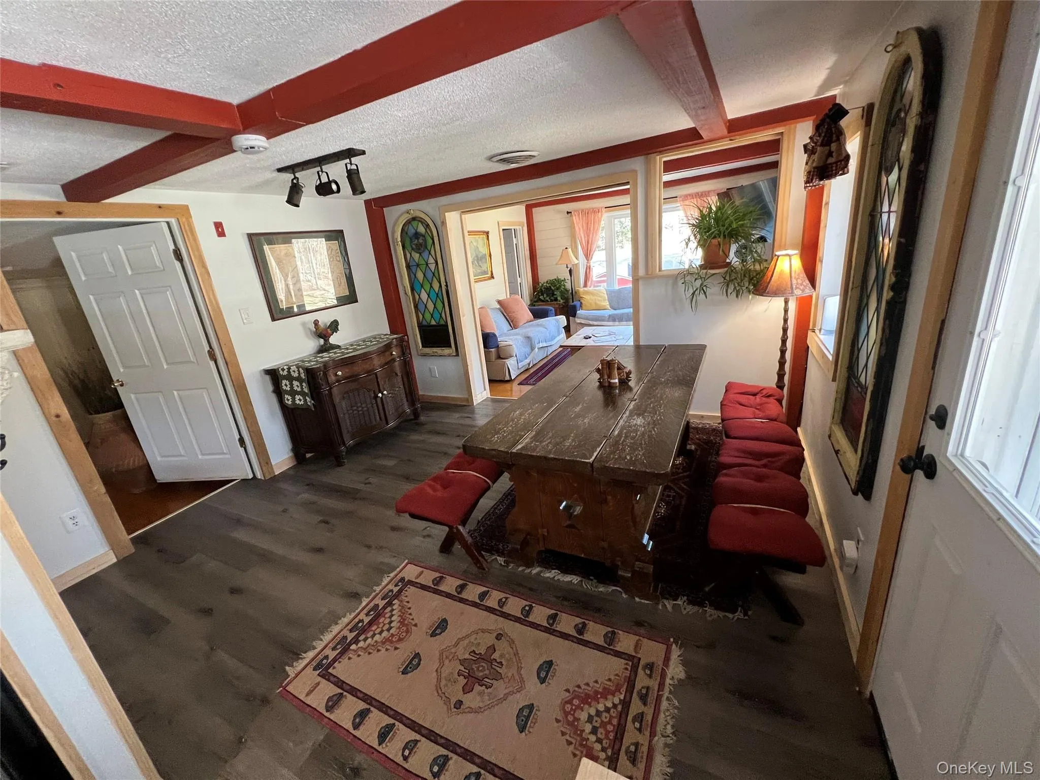 Dining room with beamed ceiling, a textured ceiling, and dark wood-type flooring Dining room with beamed ceiling, a textured ceiling, and dark wood-type flooring