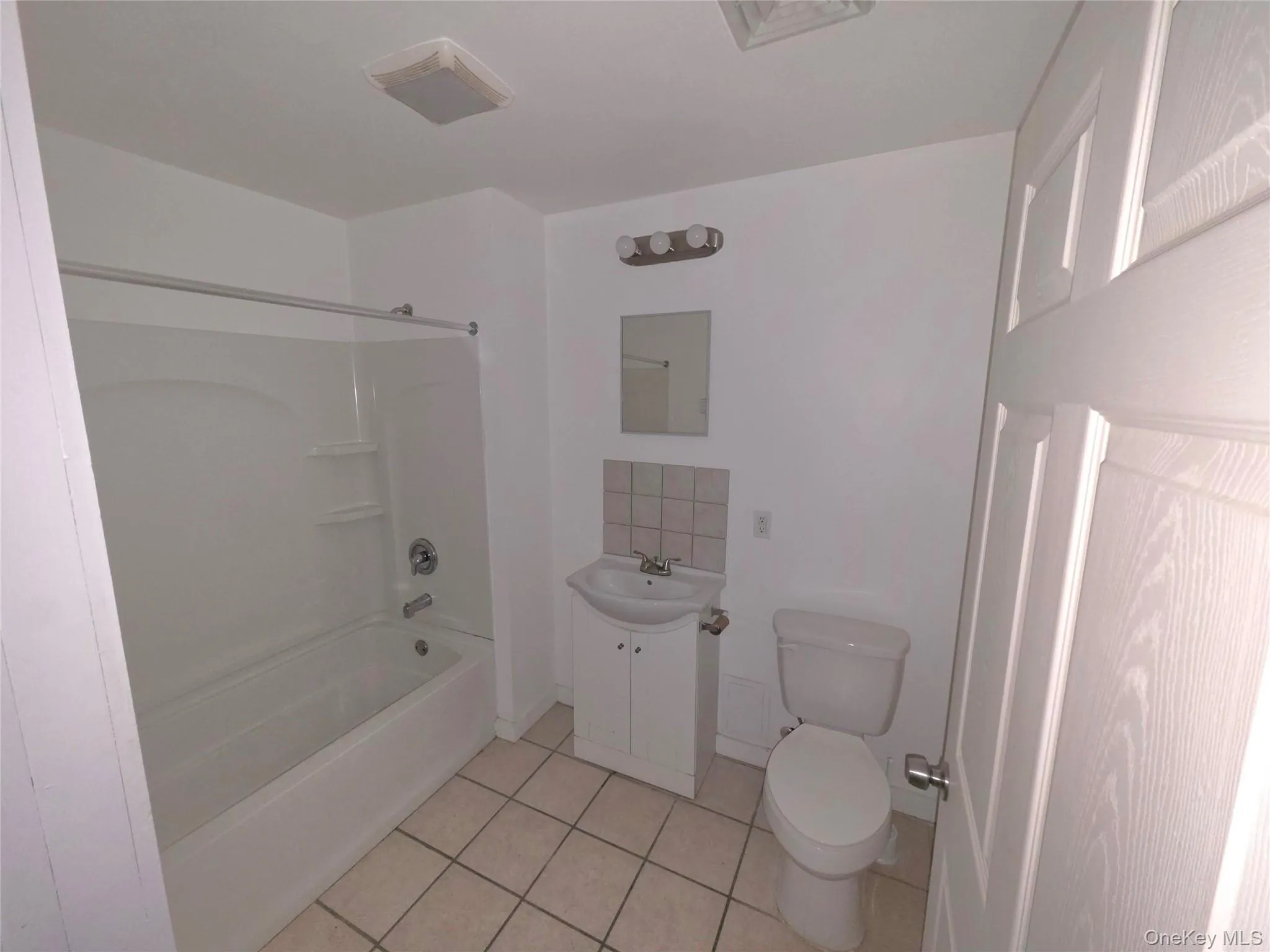 Full bathroom featuring washtub / shower combination, vanity, and light tile patterned floors Full bathroom featuring washtub / shower combination, vanity, and light tile patterned floors