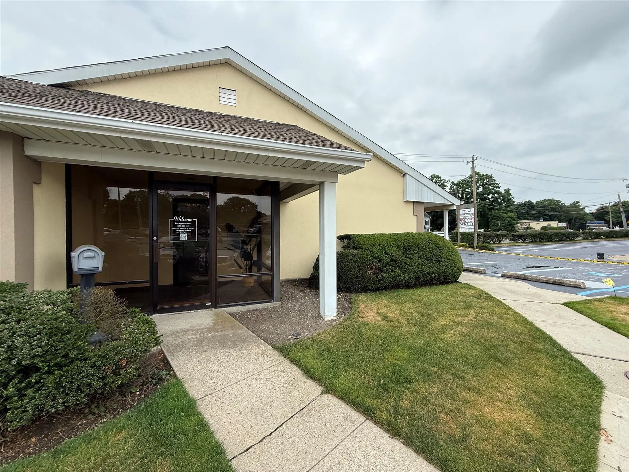 Property entrance with stucco siding, roof with shingles, and a lawn Property entrance with stucco siding, roof with shingles, and a lawn