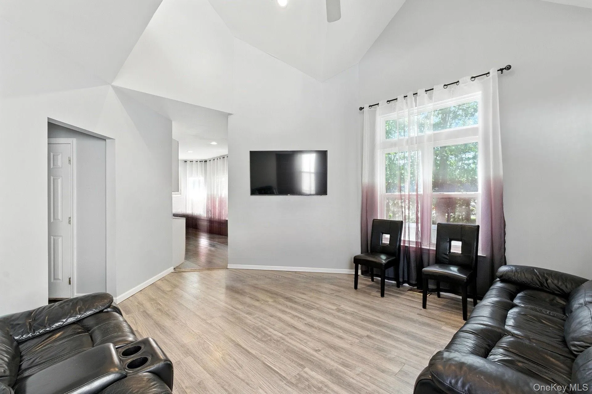 Living room featuring high vaulted ceiling, light wood finished floors, and a ceiling fan Living room featuring high vaulted ceiling, light wood finished floors, and a ceiling fan
