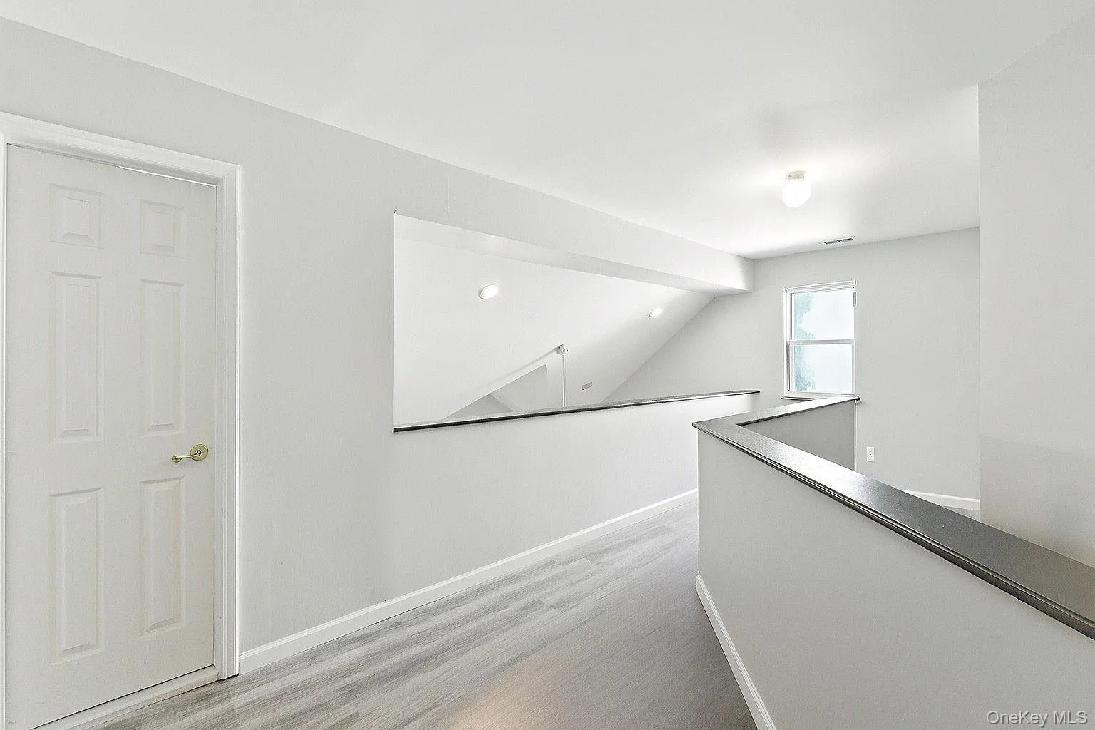 Hallway featuring an upstairs landing, light wood-style flooring, and lofted ceiling. Hallway featuring an upstairs landing, light wood-style flooring, and lofted ceiling.