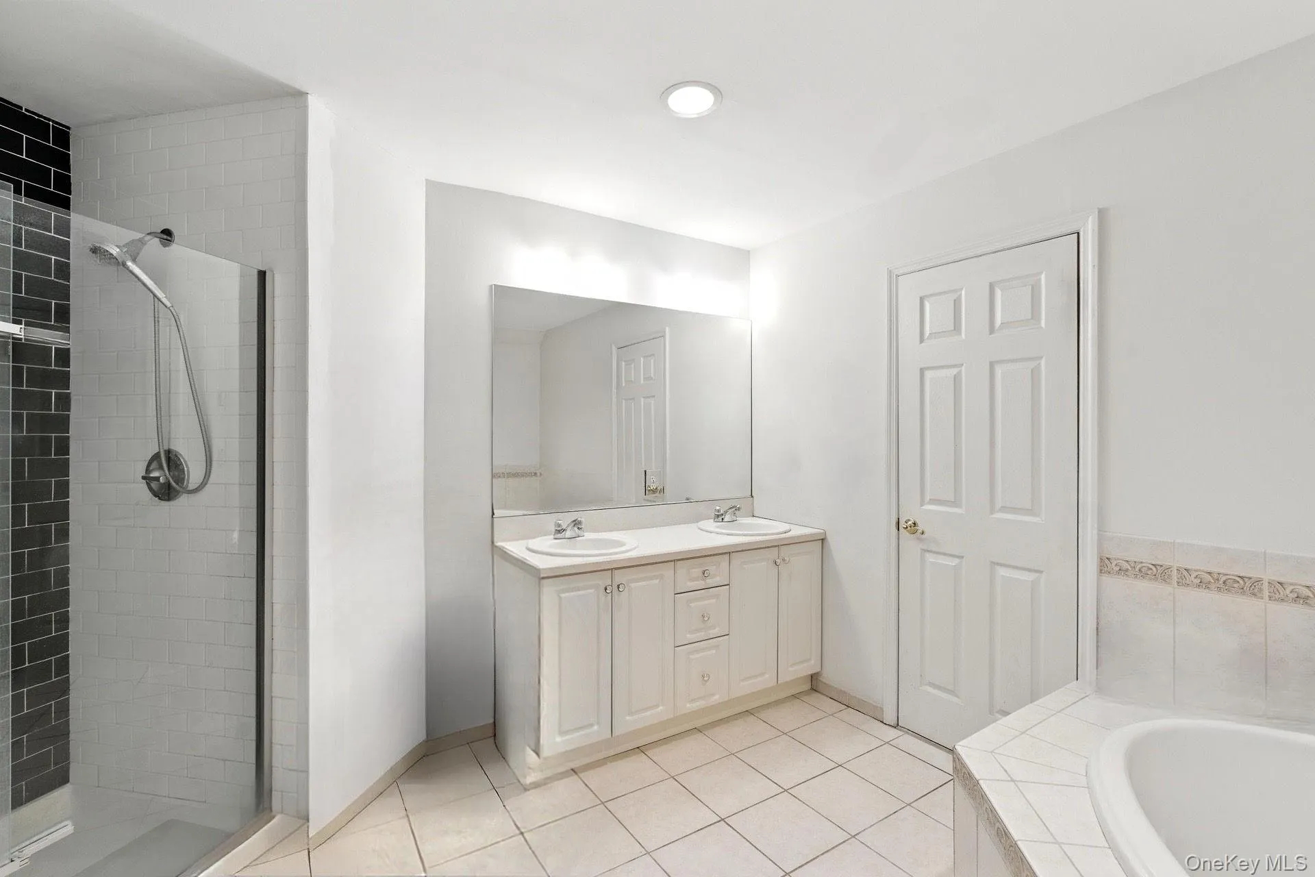Primary bathroom with double vanity, tiled shower, tile patterned floors, and recessed lighting. Primary bathroom with double vanity, tiled shower, tile patterned floors, and recessed lighting.